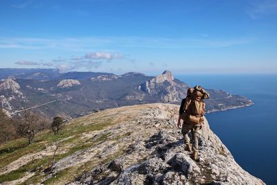 Man walking on mountain ridge against sky