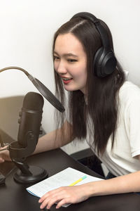 Portrait of young woman using mobile phone against white background