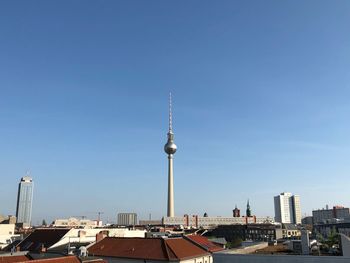 Communications tower in city against sky