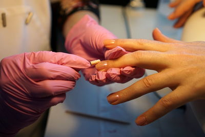 Midsection of beautician applying nail polish on female customer in salon