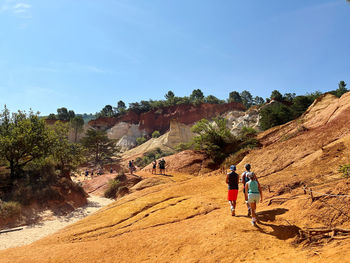 Rear view of man walking on mountain against sky