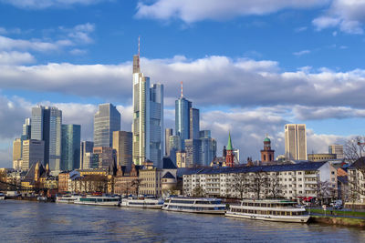 View of buildings by river against cloudy sky