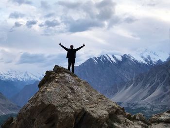 Man gesturing while standing on rock against mountains