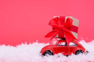 Red toy car on snow covered landscape during winter