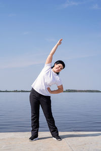 Full length of man standing by lake against sky