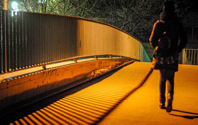 Rear view of man walking on footpath at night