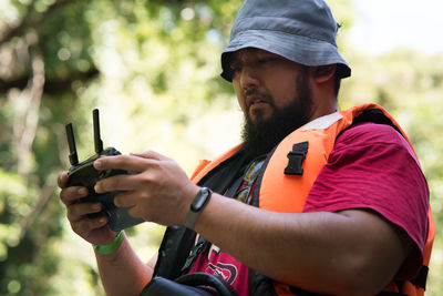 Low angle view of man holding remote control while standing outdoors