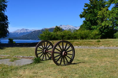 Big wheels on field against trees and mountains