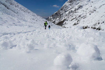 People walking on snowy landscape against sky