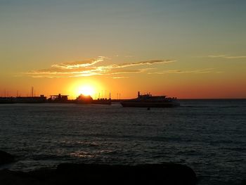 Silhouette of ship sailing on sea during sunset