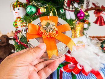 Gift box in hand on christmas tree background.