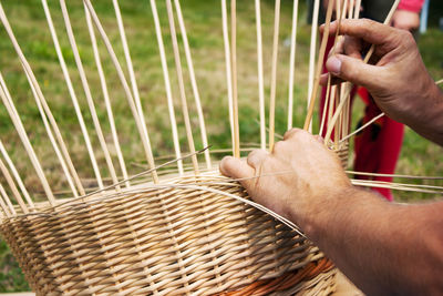 Cropped hands making wicker basket