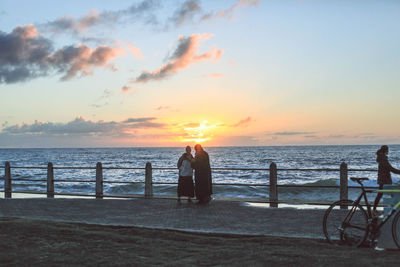 Rear view of silhouette woman on beach against sky during sunset