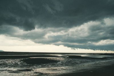 Scenic view of beach against cloudy sky