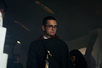 Portrait of young man standing by illuminated lighting equipment