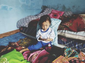 High angle view of girl sitting on bed