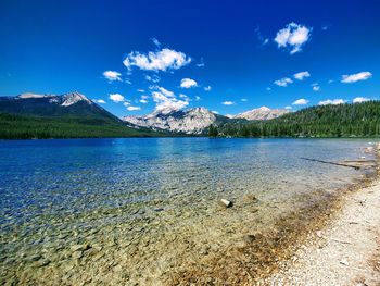 Scenic view of lake and mountains against blue sky