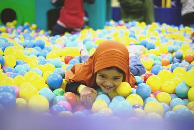 Smiling girl wearing hijab lying in ball pool