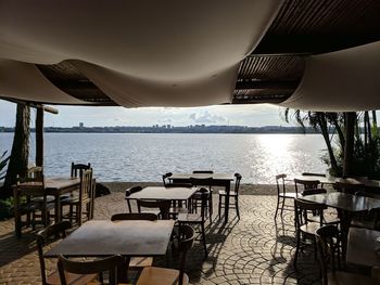 Empty chairs and tables in restaurant by sea