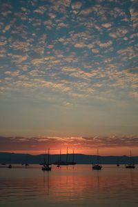 Silhouette sailboats in sea against sky during sunset