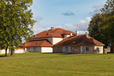 Houses on field by trees against sky