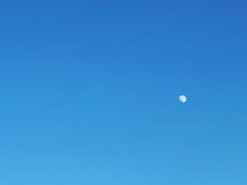 Low angle view of moon against clear blue sky