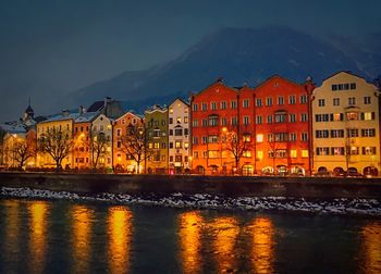 River in front of illuminated houses against sky