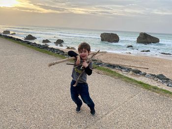 Full length of boy standing on beach against sky