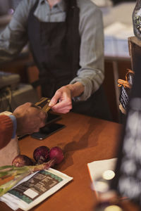 Cropped image of customer doing credit card payment to owner at store