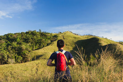 Rear view of man looking at camera on field against sky