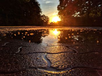 Surface level of wet shore against sky during sunset