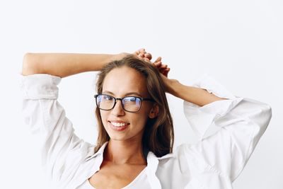 Portrait of young woman with arms crossed against white background