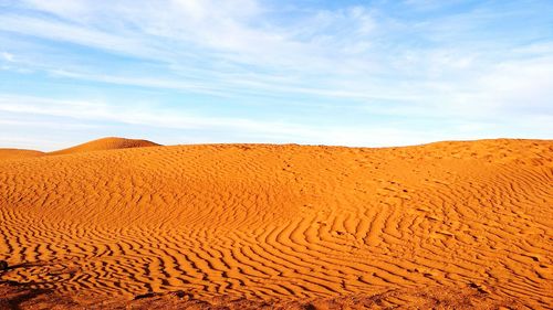 Sand dunes in desert against sky