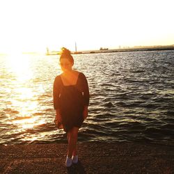 Portrait of young woman standing on beach against clear sky