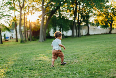 Rear view of boy running on field