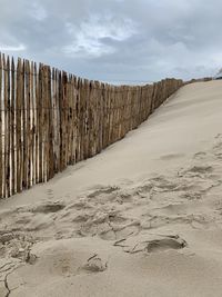 Wooden posts on beach against sky