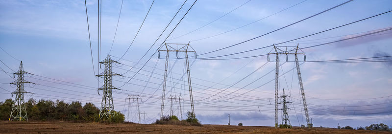 Low angle view of electricity pylon on field against sky