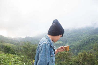 Side view of young man against mountains