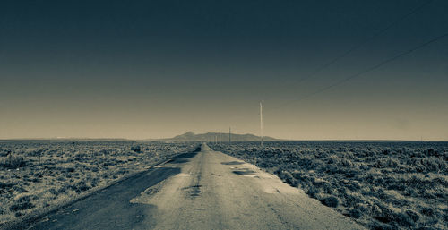 Road amidst field against clear sky