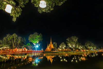 Illuminated building by river at night