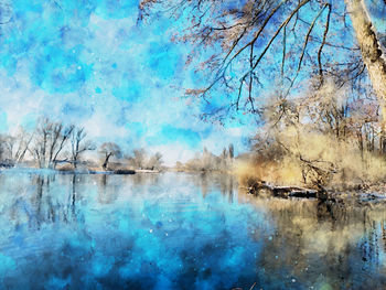 Bare trees by lake against blue sky