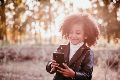 Portrait of smiling young woman using mobile phone outdoors