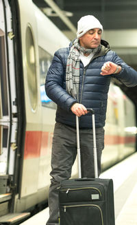 Man holding umbrella while standing by train