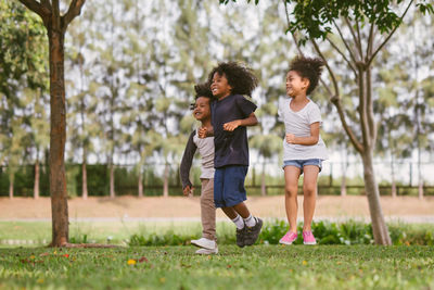 Siblings jumping over field at park