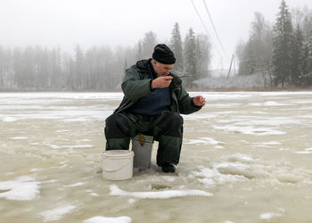 Full length of man sitting on snow covered land