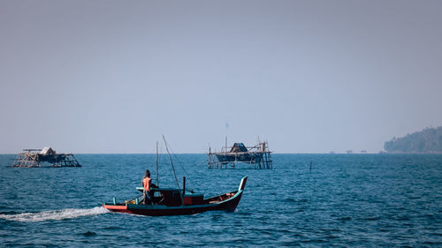 Boats sailing in sea against clear sky