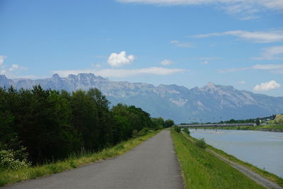 Road leading towards mountains against sky