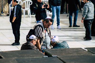 Rear view of people sitting on street