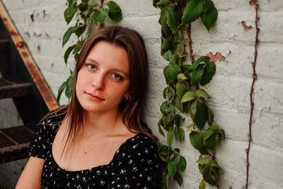 Portrait of young woman standing against wall