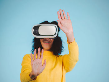 Happy woman using virtual reality simulator against blue background